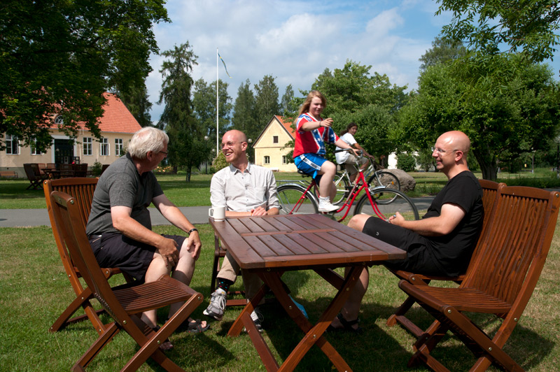 Hasse Larsson, Erik Hellsten och Ola Gustafsson sitter i solen och ger fanken i börsutvecklingen. Cyklisterna Jesper Öberg och Max del Rio Diaz håller med.